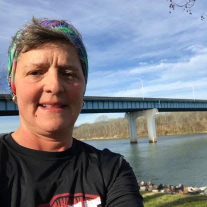 Jacque beside the river in Chattanooga, with a bridge behind her