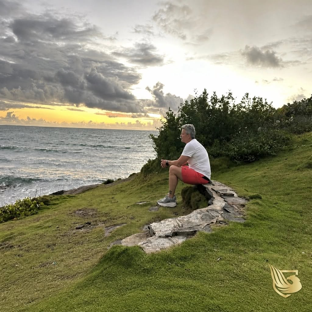 Jacque sitting on a bluff above the water at sunrise