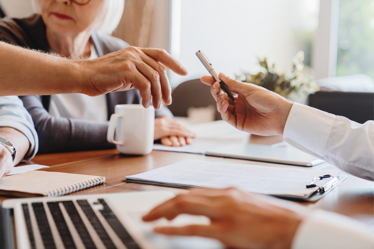 An older client reviewing estate paperwork with an advisor across a table